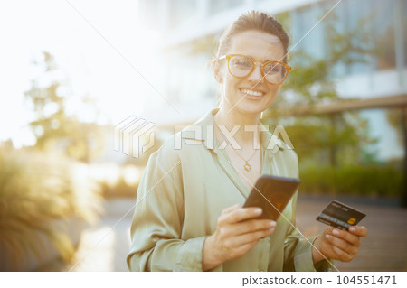 female worker in green blouse and eyeglasses using smartphone female worker in green blouse and eyeglasses using smartphone 104551471