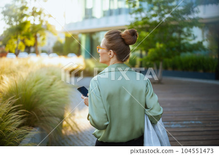 Seen from behind business woman near business center using phone Seen from behind business woman near business center using phone 104551473