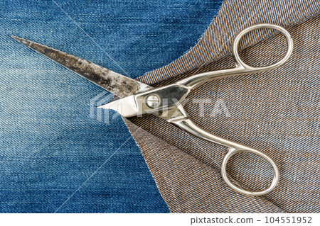 Metal scissors and ripped denim jeans Metal scissors and ripped denim jeans 104551952