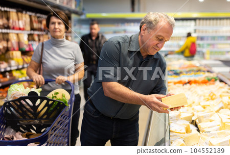 Older man picking out fresh cheese to buy in grocery store Older man picking out fresh cheese to buy in grocery store 104552189