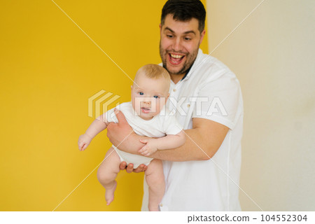 Positive cheerful dad holds his son in his arms. Happy parent and baby 104552304