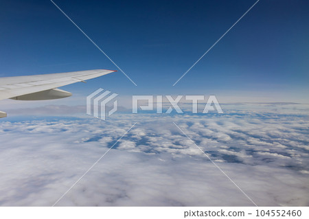 View from airplane window reveals breathtaking panorama of Earth below boundless expanse blue sky above 104552460