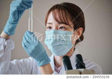 一個穿白大衣的年輕女人在做實驗 一個穿白大衣的年輕女人在做實驗 104553230