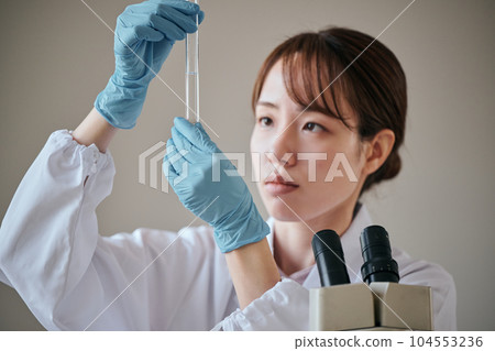 一個穿白大衣的年輕女人在做實驗 一個穿白大衣的年輕女人在做實驗 104553236
