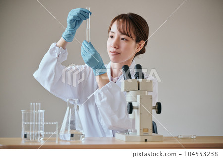 一個穿白大衣的年輕女人在做實驗 104553238