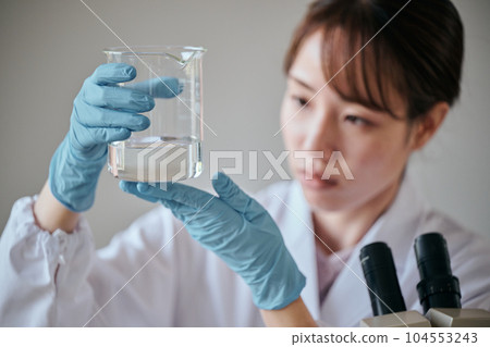 A young woman in a white coat doing an experiment A young woman in a white coat doing an experiment 104553243