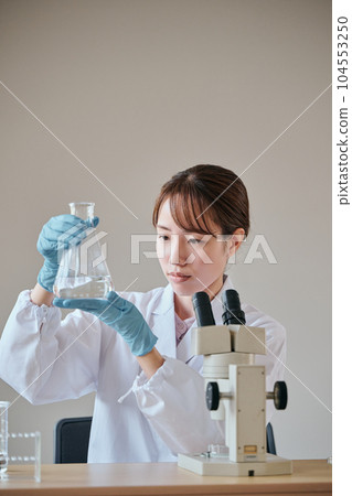 一個穿白大衣的年輕女人在做實驗 一個穿白大衣的年輕女人在做實驗 104553250