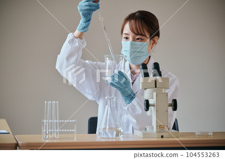 一個穿白大衣的年輕女人在做實驗 一個穿白大衣的年輕女人在做實驗 104553263