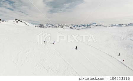 Livigno, Italy - February 21, 2022: People snowboarding skiing at ski resort. Skiers, snowboarders riding snowy mountain slope. Outdoor winter sport, scineric panoramic view.  104553316