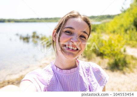 Nature's Selfie: Attractive Brunette Capturing Summer Memories by the Forest Lake, Attractive young 104553454