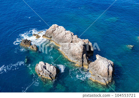 Stormy waves hitting rocks in blue Ionian sea 104553721
