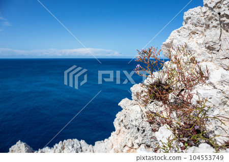 Rocky steep cliff close-up on blue Ionian seascape Rocky steep cliff close-up on blue Ionian seascape 104553749