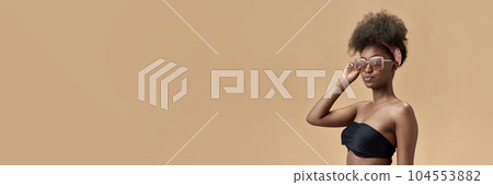 Portrait of attrcative, stylish, young african woman in top and trendy sunglasses against studio background Portrait of attrcative, stylish, young african woman in top and trendy sunglasses against studio background 104553882