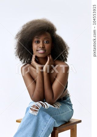 Beautiful, young, african woman with curly hair, smooth, healthy skin smiling, posing against white studio background 104553915