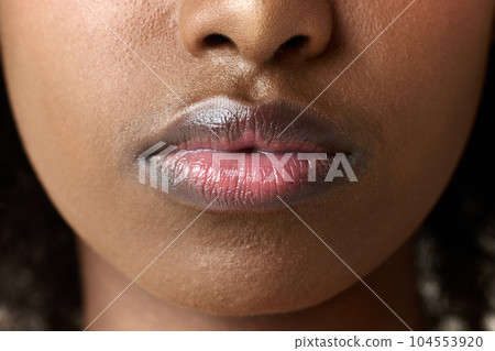 Close-up image of young african woman, female lips. Lip augmentation, care, permanent makeup, moisturizing products Close-up image of young african woman, female lips. Lip augmentation, care, permanent makeup, moisturizing products 104553920