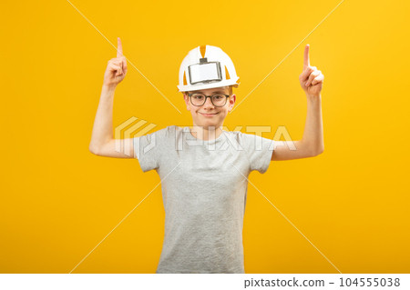 Portrait of smiling teenage boy wears protective helmet points his index fingers up. Copy space. Space for text Portrait of smiling teenage boy wears protective helmet points his index fingers up. Copy space. Space for text 104555038
