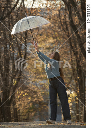 Beautiful young woman fun with transparent umbrella. Happy young woman with long hair in autumn park. Beautiful young woman fun with transparent umbrella. Happy young woman with long hair in autumn park. 104555103