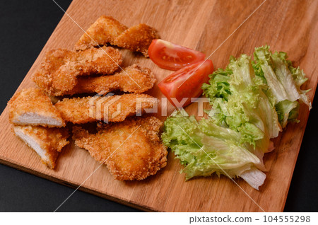 Chicken nuggets on a wooden board on a black background 104555298