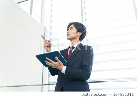 Young businessman looking at tablet in lobby 104555318