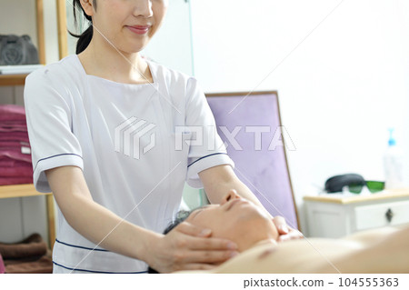 Young esthetician woman performing treatment on a man Young esthetician woman performing treatment on a man 104555363