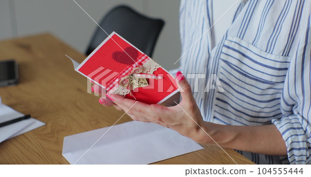 Woman received a letter with a greeting card. Close-up woman hands pull greeting card out envelope. Woman received a letter with a greeting card. Close-up woman hands pull greeting card out envelope. 104555444