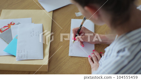 Close up female hands putting letter in envelop return form. Woman sends a return form by letter. Close up female hands putting letter in envelop return form. Woman sends a return form by letter. 104555459