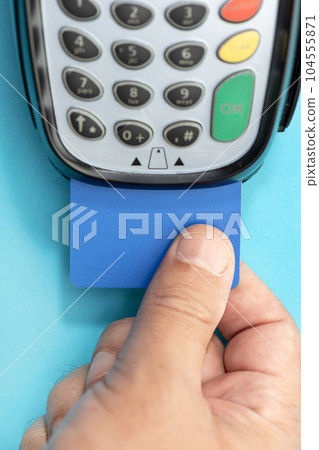 Hand put Credit card into payment terminal on blue background Hand put Credit card into payment terminal on blue background 104555871