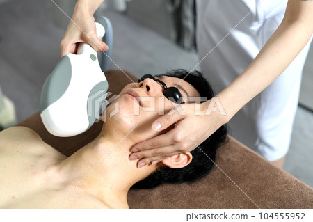 Young man undergoing beard hair removal treatment 104555952