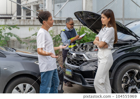 An unset young woman talking angryly to a man who accidentally drove his car and hit her car while insurance agent checking the damage of the accident An unset young woman talking angryly to a man who accidentally drove his car and hit her car while insurance agent checking the damage of the accident 104555969
