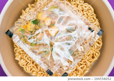 Opened Package with Uncooked Instant Noodles on Violet Background 104556052