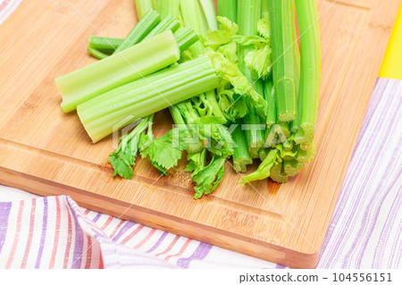 Fresh Celery Stem and Chopped Celery Sticks on Wooden Cutting Board Fresh Celery Stem and Chopped Celery Sticks on Wooden Cutting Board 104556151