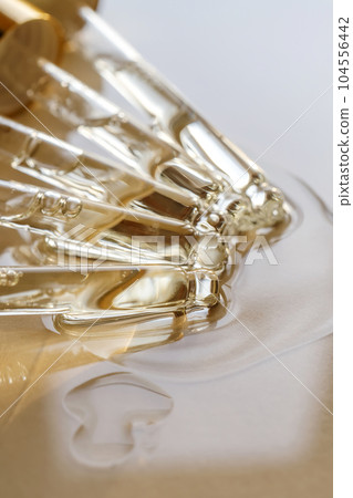 Pipettes with oil or serum on a golden background. 104556442