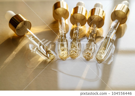 Pipettes with oil or serum on a golden background. Pipettes with oil or serum on a golden background. 104556446