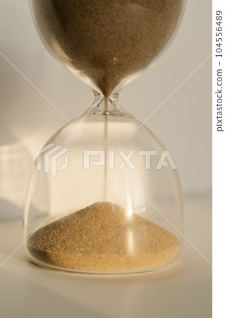 Transparent hourglass on a white sunny background. 104556489