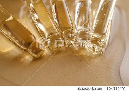Pipettes with oil or serum on a golden background. Pipettes with oil or serum on a golden background. 104556491