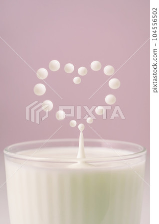 Milk drips into a transparent faceted glass. Milk drips into a transparent faceted glass. 104556502