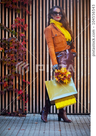 Full length portrait of trendy female in orange trench coat 104556543
