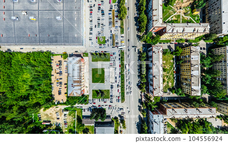 Aerial city view with crossroads and roads, houses, buildings, parks and parking lots. Sunny summer panoramic image 104556924
