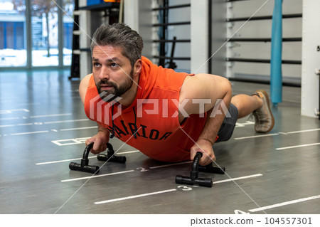 Man standing in plank position or doing exercises on push-up stands. Man standing in plank position or doing exercises on push-up stands. 104557301