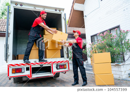 Wide shot of delivery man stand on truck and send parcel or box to his co-worker during transport 104557399