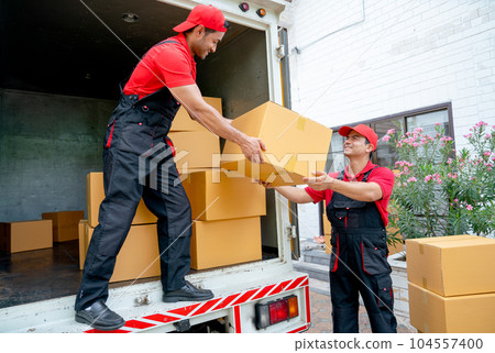 Close up of delivery man stand on truck and send parcel or box to his co-worker during transport 104557400