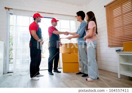 Asian man stand with his wife also shake hands to delivery men during process to send product Asian man stand with his wife also shake hands to delivery men during process to send product 104557411