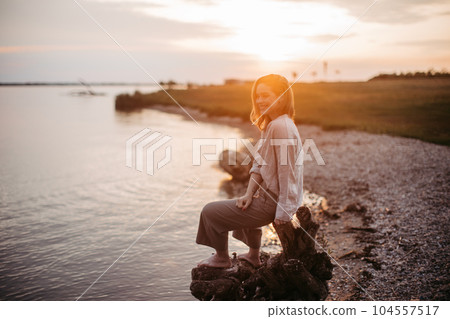 Young woman resting near lake, enjoying summer time. 104557517