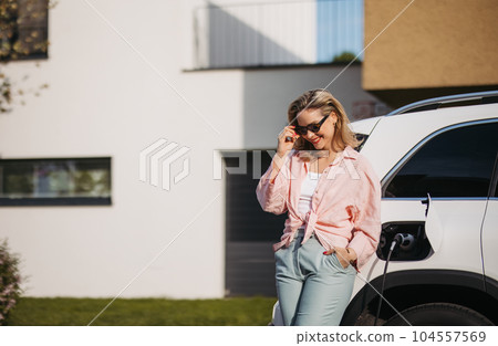 Young woman charging her electric car in home, sustainable and economic transportation concept. 104557569