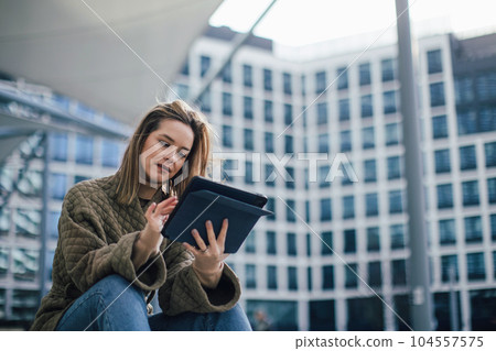 Portrait of young fashionable woman in a city with digital tablet. Portrait of young fashionable woman in a city with digital tablet. 104557575