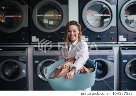 Young woman posing in a laundry room. Young woman posing in a laundry room. 104557582