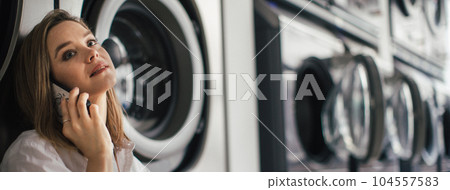 Young woman calling, waiting in a laundry room. 104557583