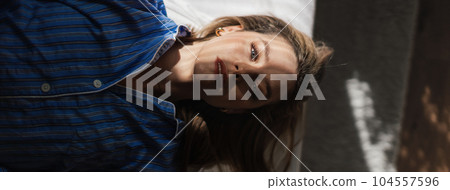 Top view of woman lying in her bed, morning sun shining on her face. 104557596