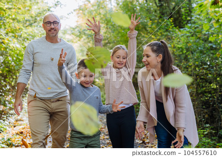 Happy family having fun with a foliage in autumn forest. 104557610