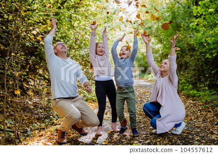 Happy family having fun with a foliage in autumn forest. 104557612